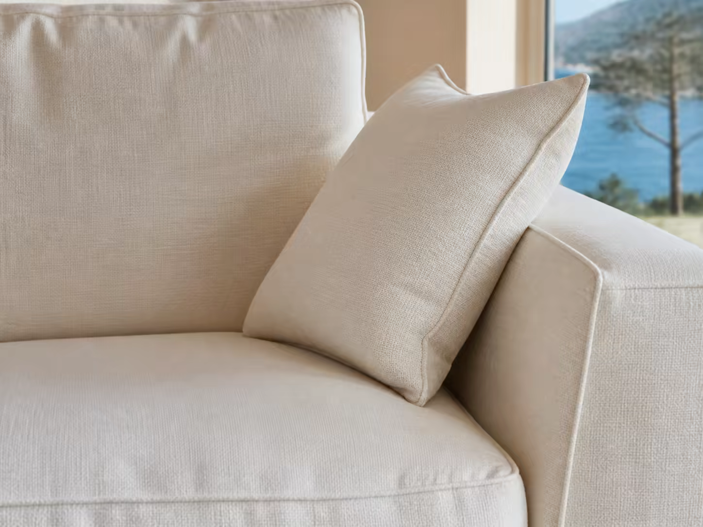 Coussins, coutures et accoudoir d’un canapé en lin ivoire