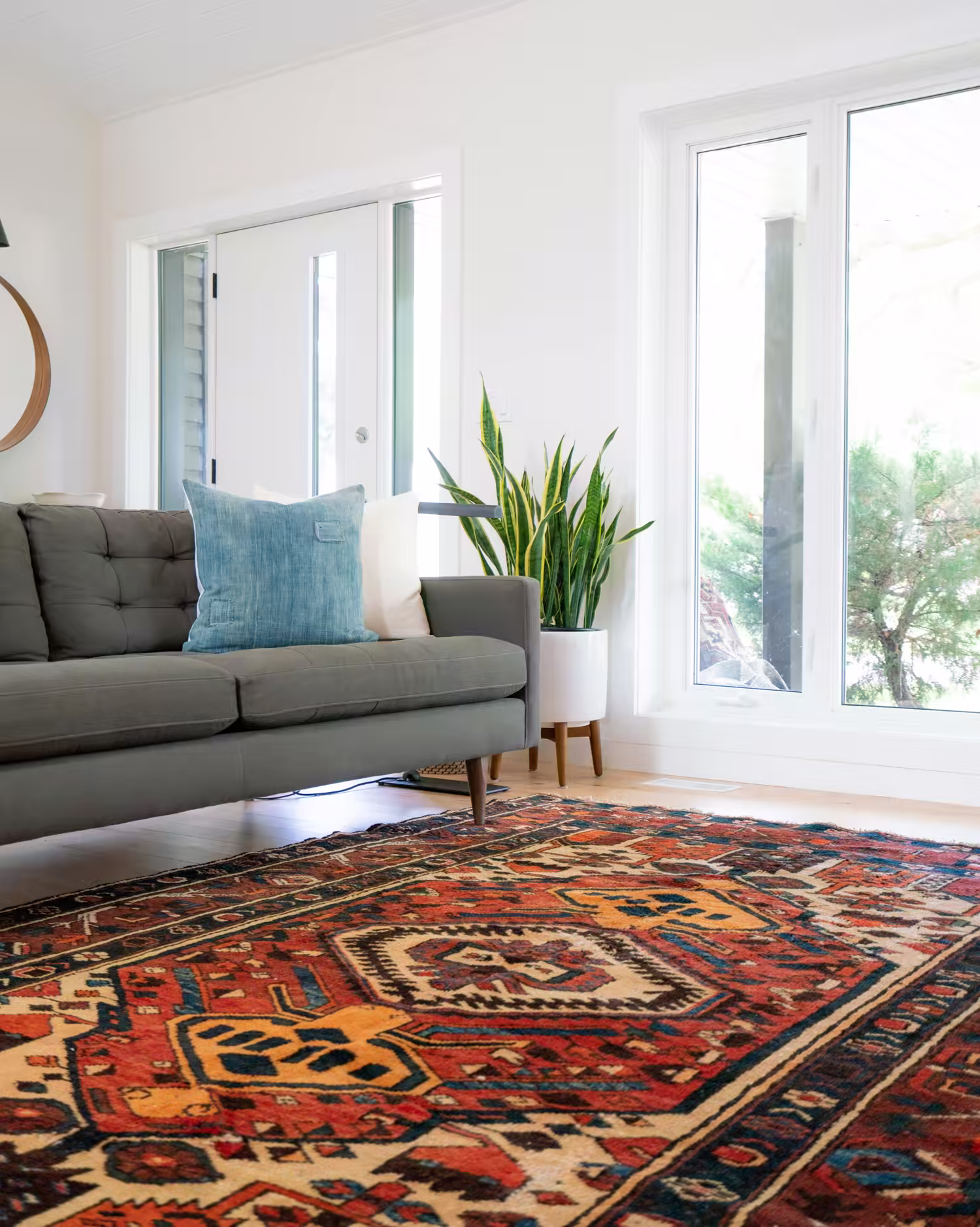 Canapé bleu vert posé sur un tapis rouge à motifs