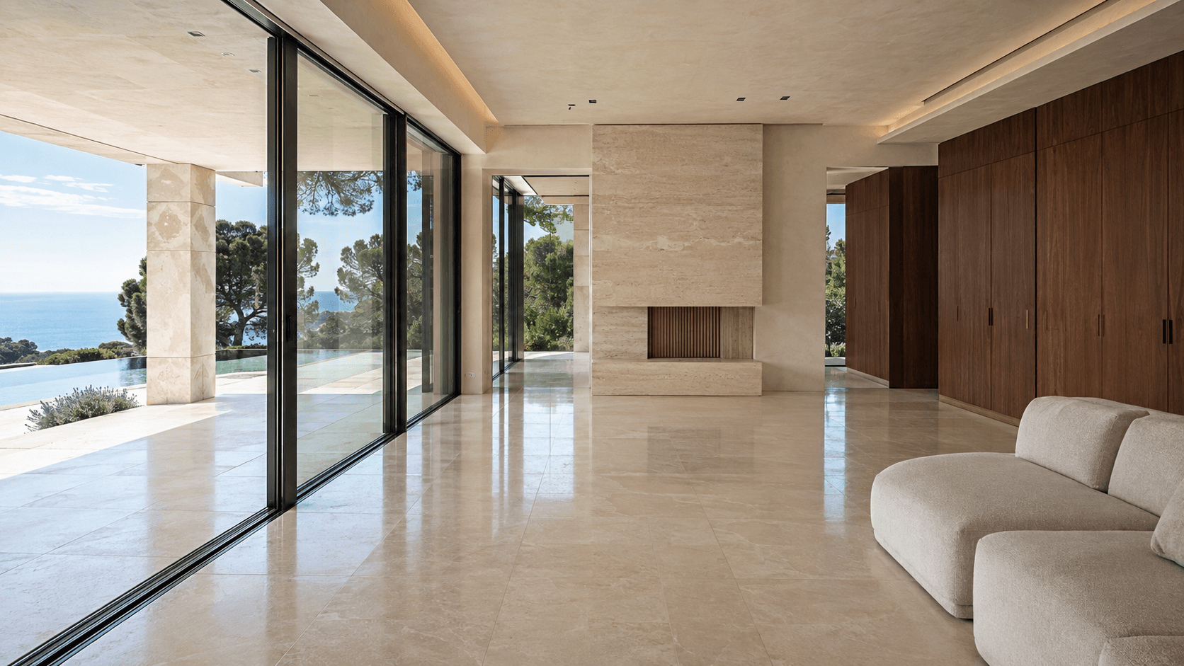 Intérieur de villa contemporaine avec sol en pierre, menuiseries en bois et grandes baies ouvertes sur la Méditerranée