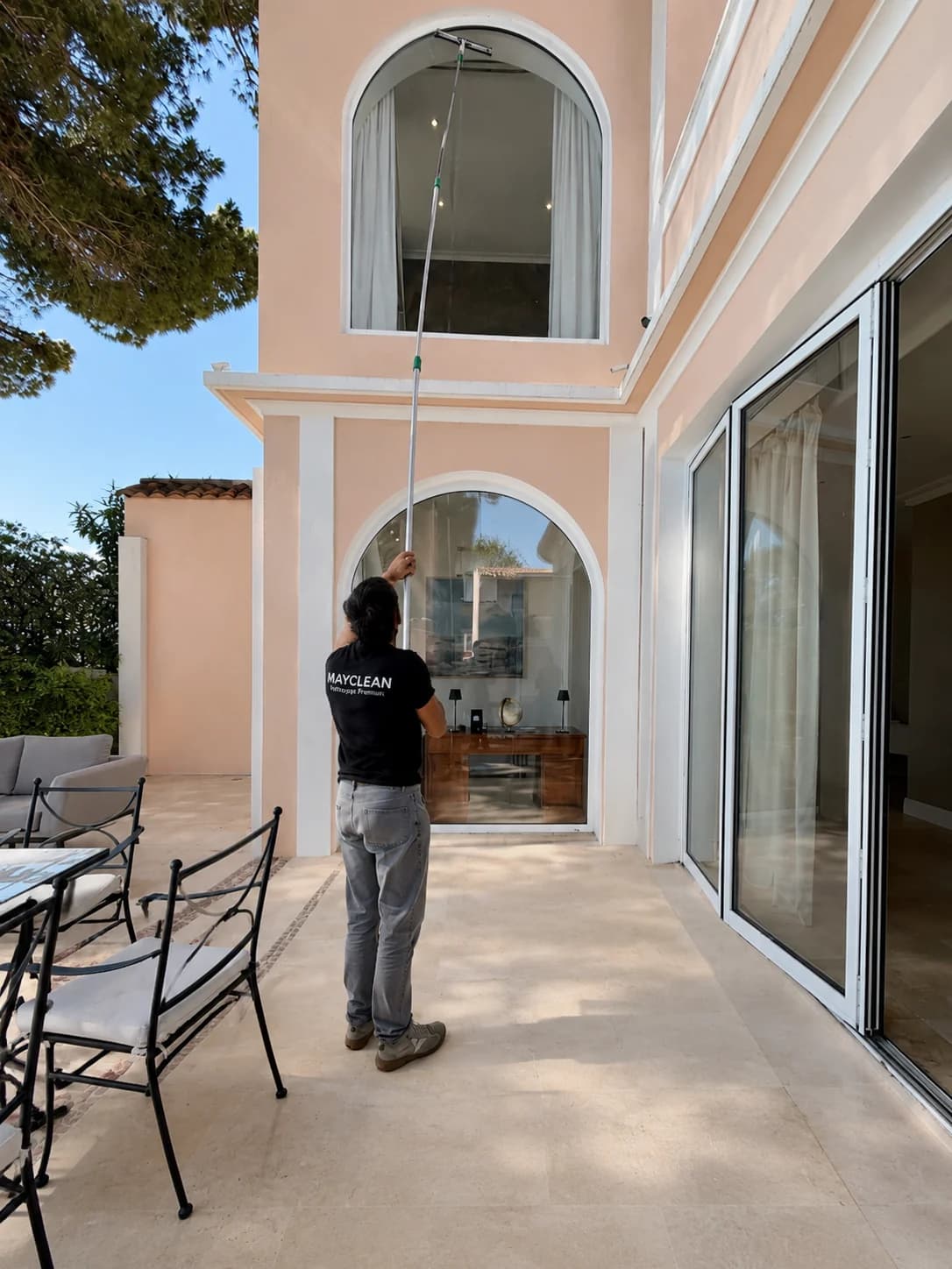 Intervenante MayClean utilisant une perche pour nettoyer un vitrage de villa